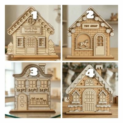 A set of four Freestanding Festive Layered Houses crafted from MDF, showing the painted 3D Toy Shop, North Pole Workshop, Winter Scene, and Town House standing on a wooden surface.